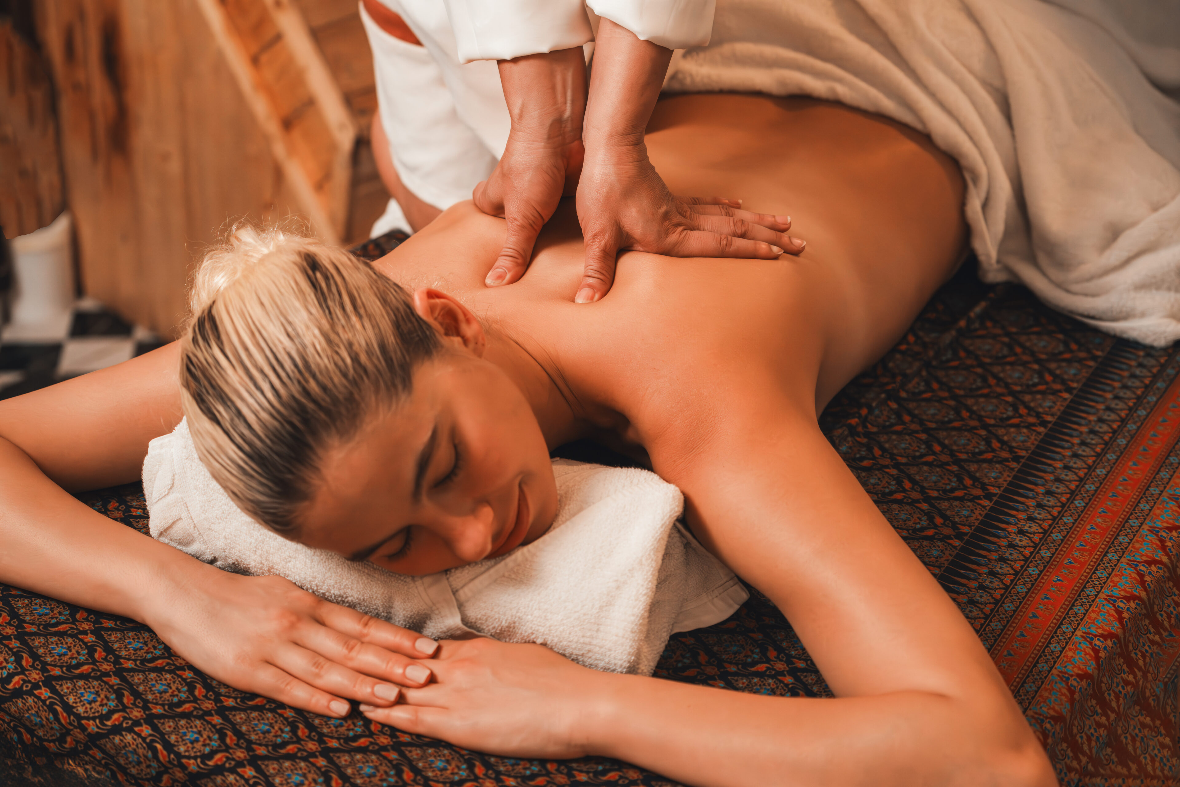Beautiful caucasian woman having back massage in front of wooden sauna cabinet. Attractive woman feel deep in relaxation surrounded by aroma and essential oil. Relaxing and calm concept. Tranquility.